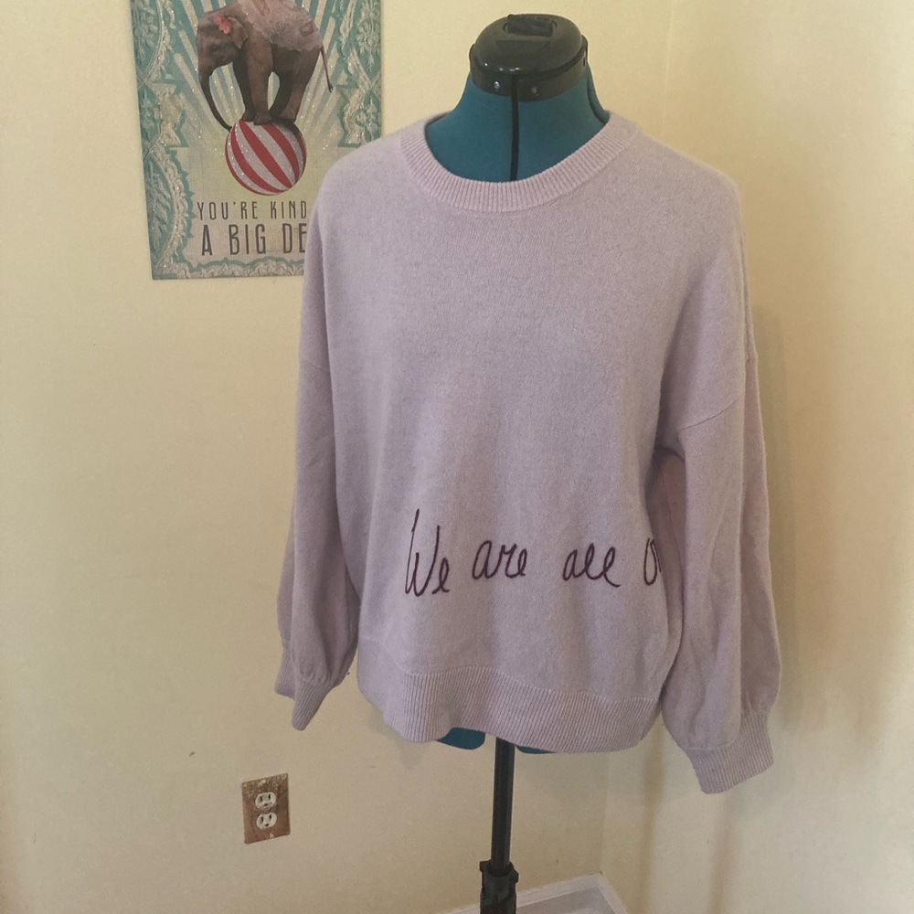 Cashmere spiritual gangster sweater- pale purple reads “we are all one”.